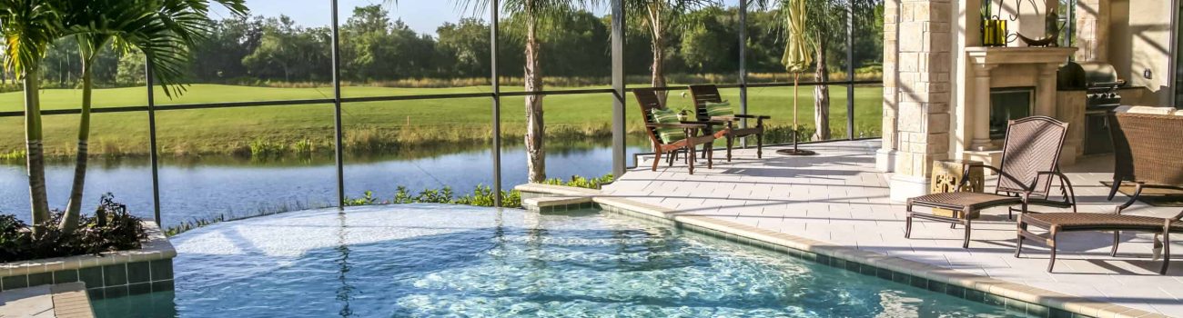 Swimming pool in new luxury home.  Patio and lounge chairs. Palm trees and lake in distance. Lifestyle background.