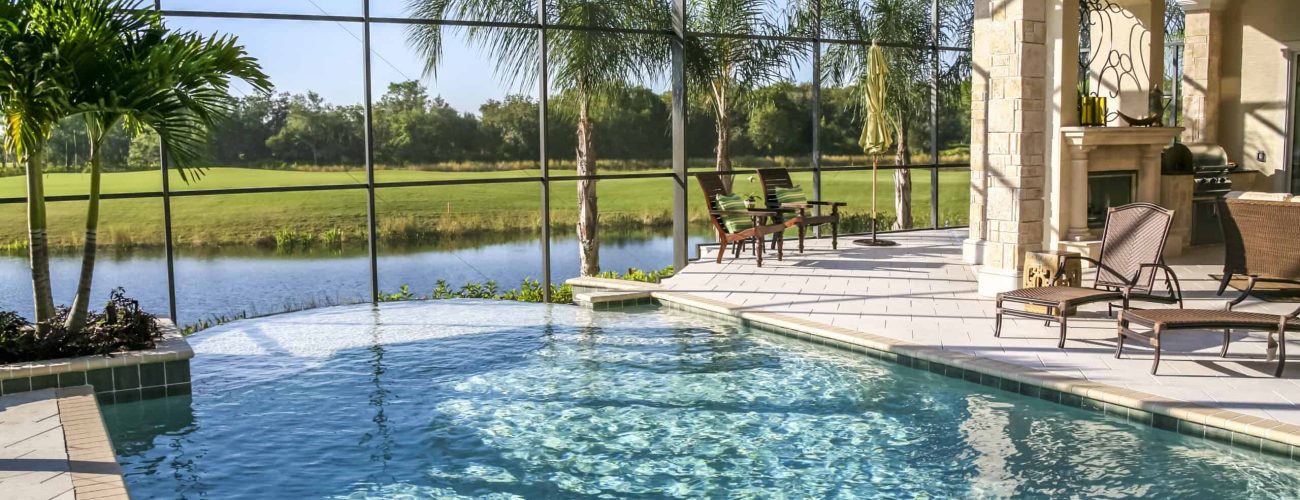 Swimming Pool Swimming pool in new luxury home. Patio and lounge chairs. Palm trees and lake in distance. Lifestyle background.
